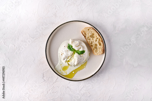 Italian burrata cheese with ciabatta bread and olive oil on white plate. Top view, copy space