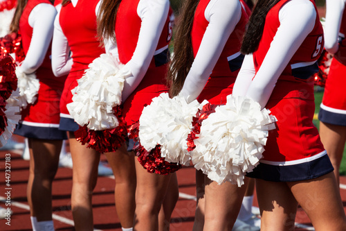 Cheerleaders holding pom poms behind them