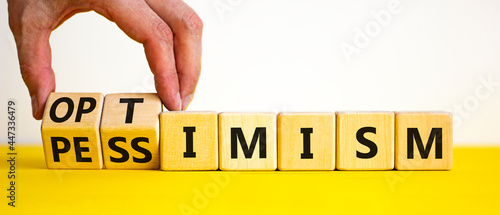 Pessimism or optimism symbol. Businessman turns cubes and changes the word 'pessimism' to 'optimism'. Beautiful yellow table, white background. Business, optimism or pessimism concept. Copy space.