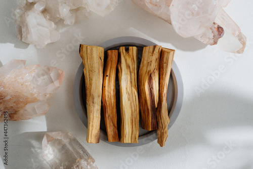 Palo Santo sticks on a concrete plate and natural crystals, beautifully illuminated by sunlight. Set of incense for fumigation. Top view. Organic sacred tree incense from Latin America.