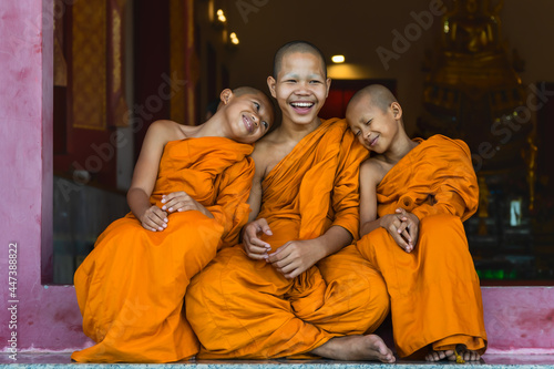 buddhist novice monks smiling and sitting together at temple gate
