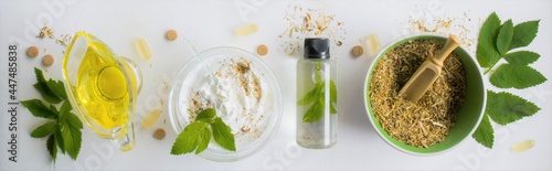 Banner with alternative medicine, herbal extracts white background, jar of oil over a bowl with white essence. Bowl with ground dry medicinal herbs, green leaves and pills. Copy space