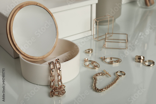 Jewelry box with mirror and stylish golden bijouterie on white dressing table