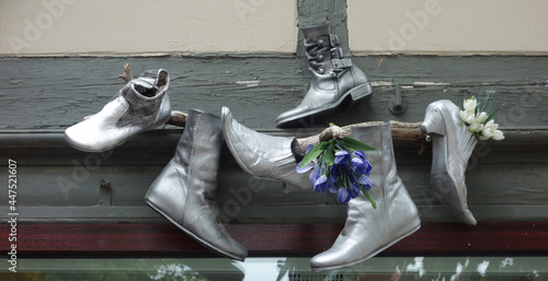 work of art with various boots painted silver and nailed to a wooden board, Warnemunde, Rostock, Germany
