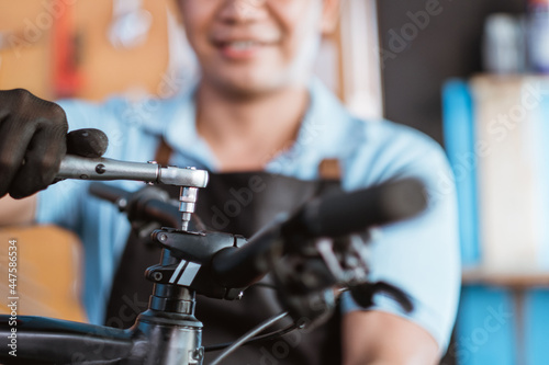 close up of the hands of a bicycle mechanic wearing gloves using a shock wrench to remove the handlebar bolts in a workshop