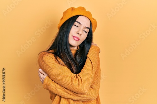 Young brunette woman wearing french look with beret hugging oneself happy and positive, smiling confident. self love and self care
