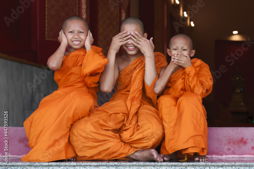 three Thai buddhist novice monk smiling and sitting together