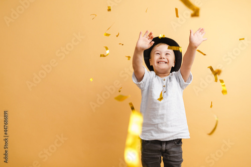 White boy with down syndrome in hat playing with confetti