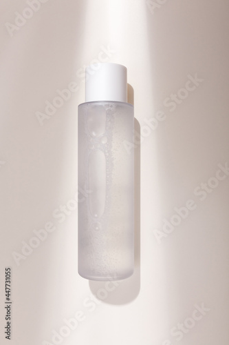 Mock up bottle of essence toner with no label in trendy natural light. Face skin care cosmetics, moisturizer, copy space