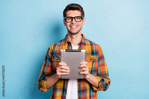 Portrait of attractive cheerful guy geek holding in hands using device app 5g isolated over bright blue color background