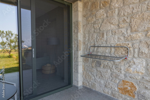 View of outdoor clothes dryer on patio of hotel room. Mosquito net protection on door. Greece. 