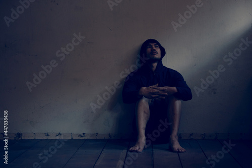 Depressed and hopeless asian man sitting alone after using drugs sitting on the floor. Drugs addiction and withdrawal symptoms concept.