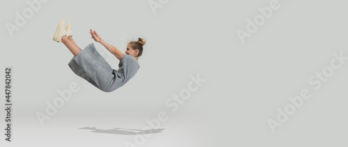 Studio shot of little preschool caucasian girl in casual clothes falling down isolated over white studio background.