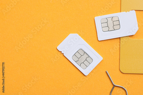 Modern SIM cards and needle on orange background, flat lay. Space for text
