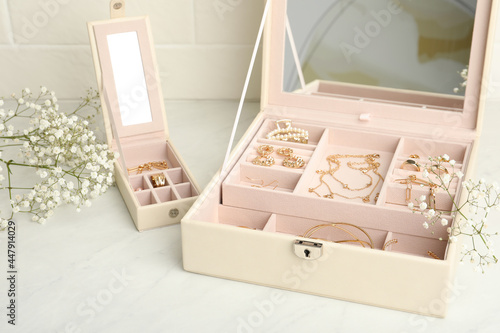Jewelry boxes with different elegant bijouterie and flowers on white table
