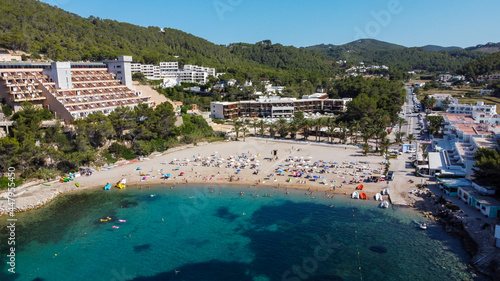Aerial view of the beach of Port Sant Miquel on the north shore of Ibiza island in Spain - Isolated bay sided with large hillside hotels in the Balearic Islands