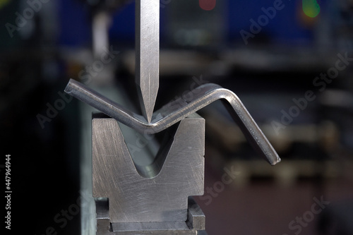 Bending sheet metal on a hydraulic machine at the factory. Bend tools, press brake punch and die. Close-up.