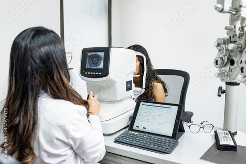 Una mujer medico de la salud visual realizando un examen de la vista a una paciente con maquinas especiales