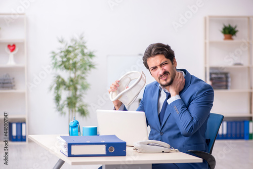 Young male employee after accident sitting at workplace