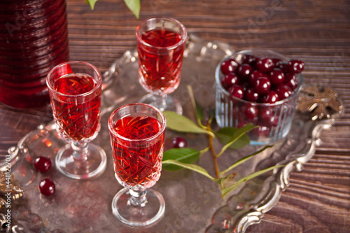 glasses of cherry brandy liqueur with ripe berries on wooden table