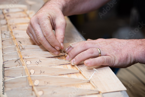 Working hands building balsa wood airplane model wing