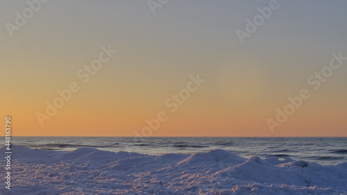 View of the sunset on a frozen lake covered by the thick ice in Ontario, Canada.