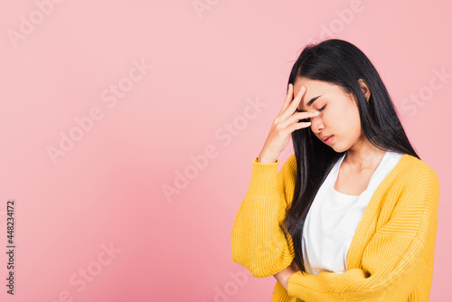 Portrait of beautiful Asian young woman sad tired strain face holding hold head by hands, female person closed eyes problem she headache, studio shot isolated on pink background