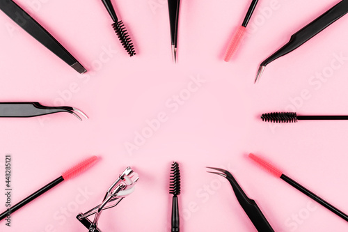 Makeup accessories. Cosmetics products. Various tools for eyelashes extensions on trendy pastel pink background. Mascara, eyelash curler, tweezers, brushes. Top view, flat lay. Copy space.