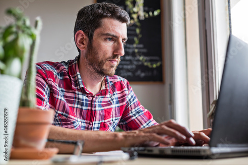 Man concentrating on work and typing on laptop