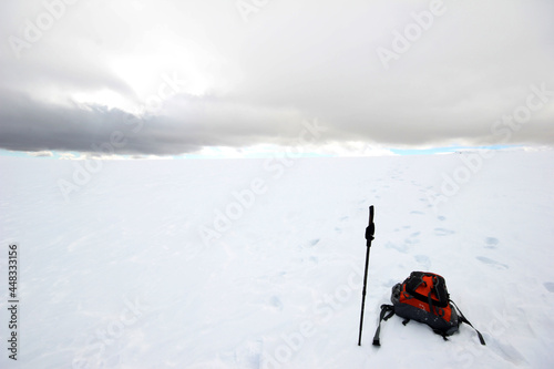 Backpack and baton on snow covered mountain. Winter sports. Walking in the snow.