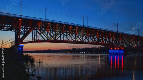 The illuminated structure of the Legionów Bridge Marshal Józef Piłsudski and the Vistula below it and the panorama of the city of Płock at dusk 