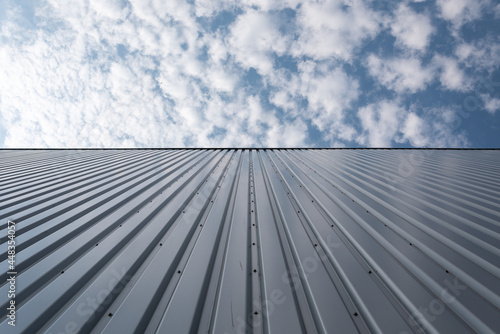 View upwards to the facade of a warehouse with a cladding of silver corrugated aluminum sheet.