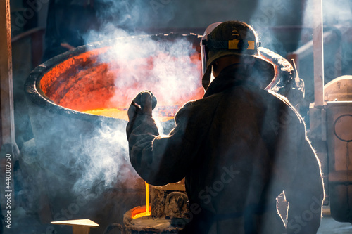 worker of metal and alloys foundry at a metallurgical plant, rear view