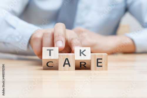 Hand of business man fliping wooden block to bulding wording of "Take care"