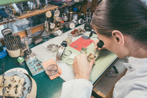 Watchmaker woman absorbed in her delicate work wearing spectacles