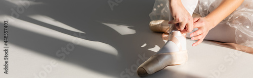 Cropped view of ballerina wearing pointe shoe on grey background, banner