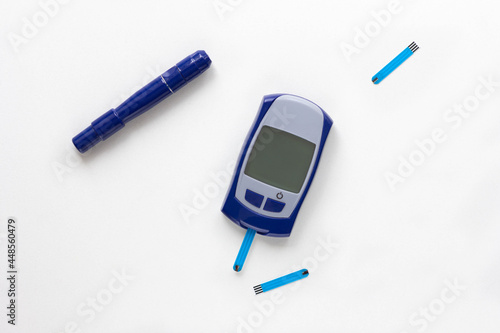 Top view of blood glucose meter, lancet and test strip in it on the white background