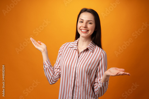 Young positive woman points fingers at copy space