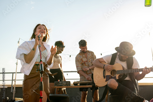 Modern music band of singer and guitarist performing at rooftop party or concert