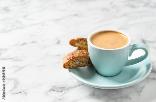 Tasty cantucci and cup of aromatic coffee on white marble table, space for text. Traditional Italian almond biscuits