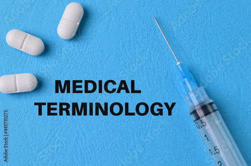 Syringe injection and pill capsules on blue background with text MEDICAL TERMINOLOGY