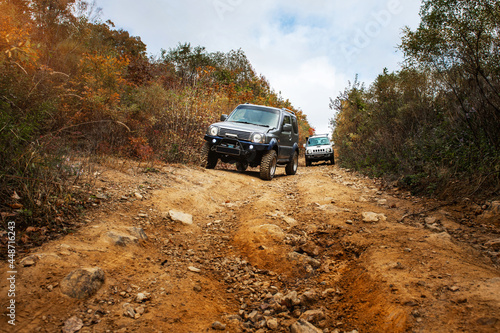 a convoy of cars is moving along a rocky road. travel by car in the taiga