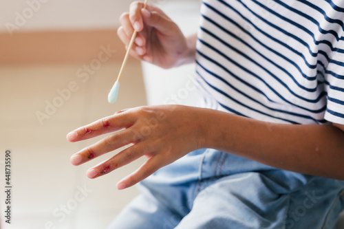 Asian child girl cleaning her wound on her finger injury and perform first aid by herself after she has been an accident.