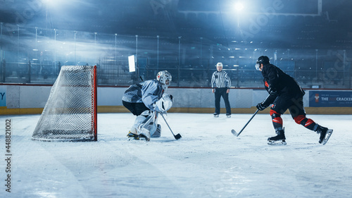 Ice Hockey Rink Arena: Goalie is Ready to Defend Score against Forward Player who Shoots Puck with Stick. Forwarder against Goaltender One on One. Tension Moment in Sport Full of Emotions.