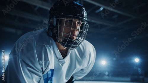 Ice Hockey Rink Arena: Confident Professional Player Ready for Faceoff and Match Start. Portrait of the Young Athlete, Determined to Win Championship, Ready to Hit that Goal.
