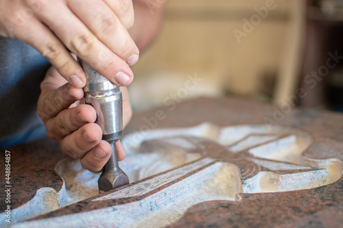 caucasian man hands bushhammered a tombstone in a workshop, work concept