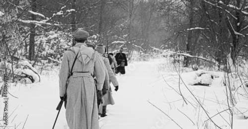Men Dressed As White Guard Soldiers Of Imperial Russian Army In Russian Civil War Times Marching Through Snowy Winter Forest. Historical Reenactment 1917-1922. Black And White Photo