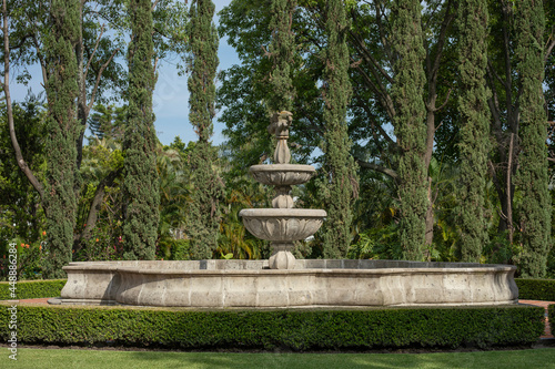 Fuente grande de piedra con arboles al fondo en un jardín