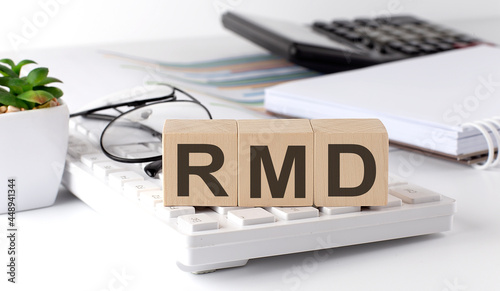 RMD required minimum distributions written on a wooden cube on keyboard with office tools