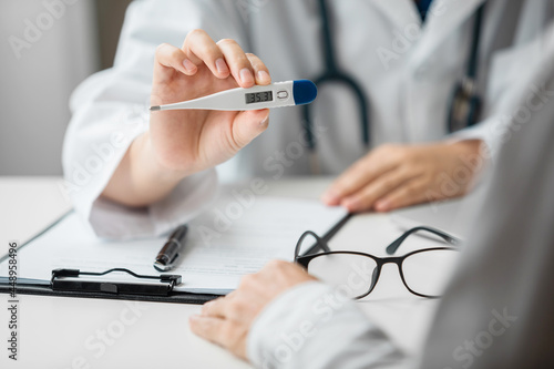 Close up of doctor using digital thermometer examination fever and diagnose disease with a patient in an examination room at a hospital, Medical and Health Care Concept.